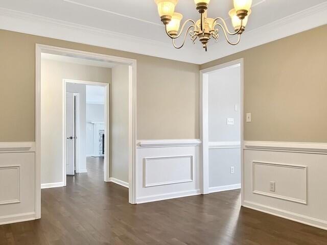 unfurnished dining area featuring crown molding, dark wood finished floors, baseboards, and an inviting chandelier