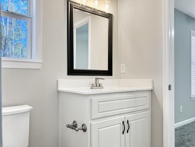 half bath with toilet, vanity, and baseboards