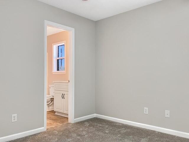 carpeted spare room featuring baseboards