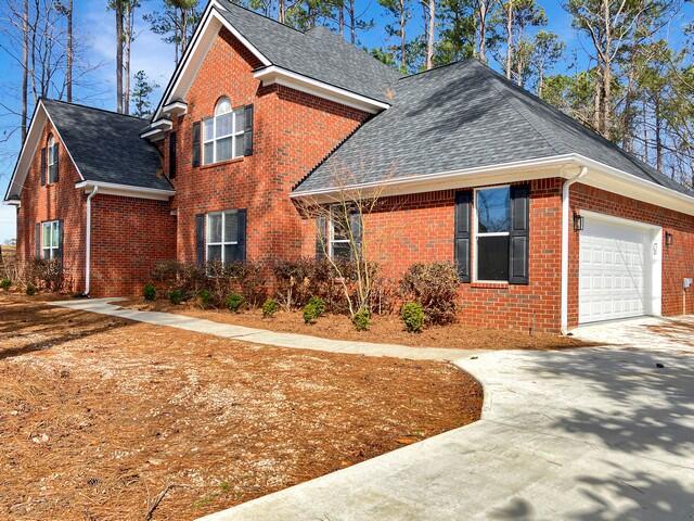 view of property exterior with driveway, brick siding, roof with shingles, and an attached garage