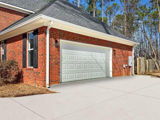 view of home's exterior with a shingled roof, concrete driveway, brick siding, and a garage