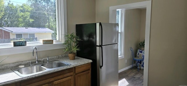 kitchen with dark wood-type flooring, stainless steel fridge, and sink