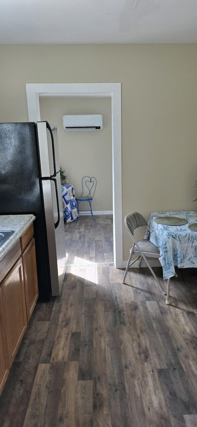 kitchen with dark hardwood / wood-style flooring, stainless steel fridge, and a wall unit AC