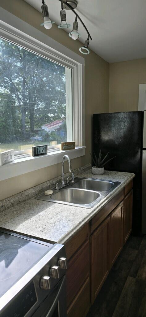 kitchen featuring black refrigerator, dark wood-type flooring, sink, and stove