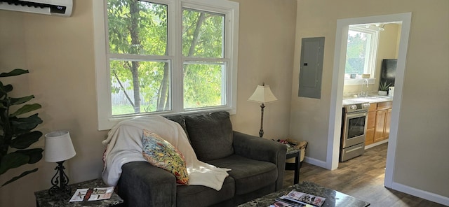 living area featuring light hardwood / wood-style flooring, electric panel, and a wall mounted AC