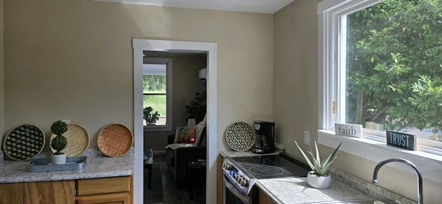 kitchen with light stone countertops, sink, stainless steel range with electric cooktop, and an AC wall unit