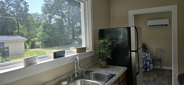 kitchen featuring a wall mounted air conditioner, sink, hardwood / wood-style floors, and stainless steel refrigerator