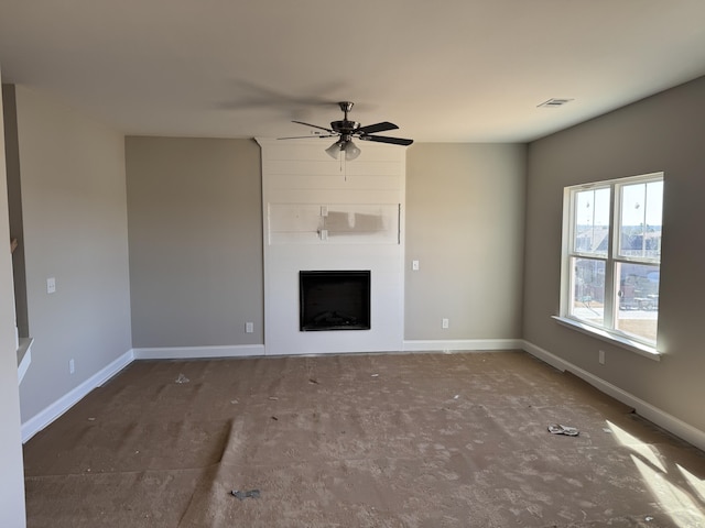 unfurnished living room featuring a large fireplace and ceiling fan