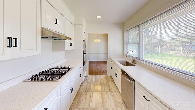 kitchen featuring under cabinet range hood, white cabinetry, appliances with stainless steel finishes, and a sink