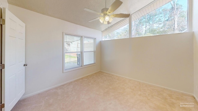 empty room with carpet floors, ceiling fan, baseboards, and a textured ceiling