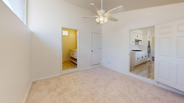 unfurnished bedroom featuring high vaulted ceiling, light carpet, visible vents, and ensuite bathroom