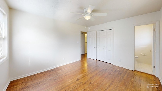 unfurnished bedroom with ensuite bathroom, a closet, light wood-type flooring, and baseboards