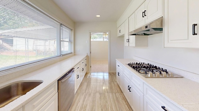 kitchen with stainless steel appliances, white cabinets, under cabinet range hood, and light stone countertops