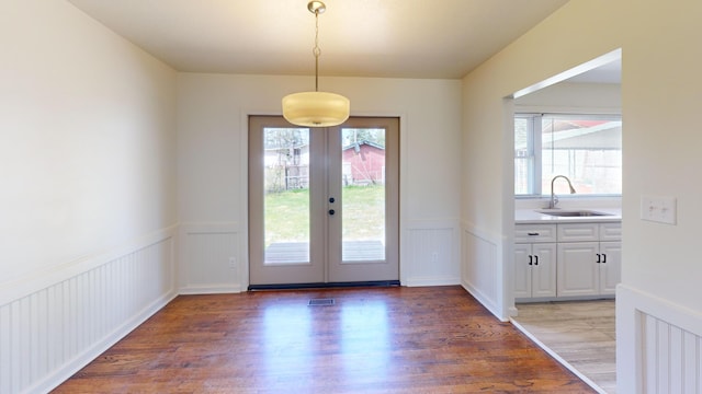 doorway with a wainscoted wall, a healthy amount of sunlight, a sink, and wood finished floors