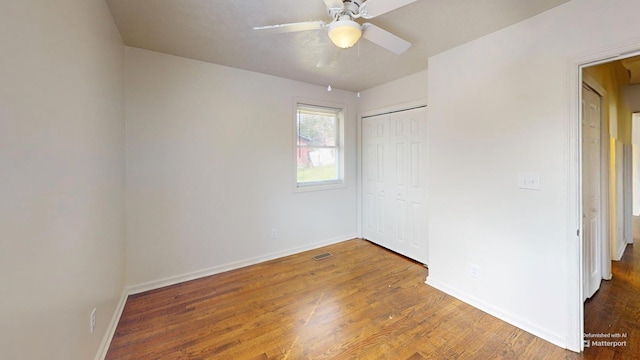 unfurnished bedroom featuring baseboards, visible vents, ceiling fan, wood finished floors, and a closet