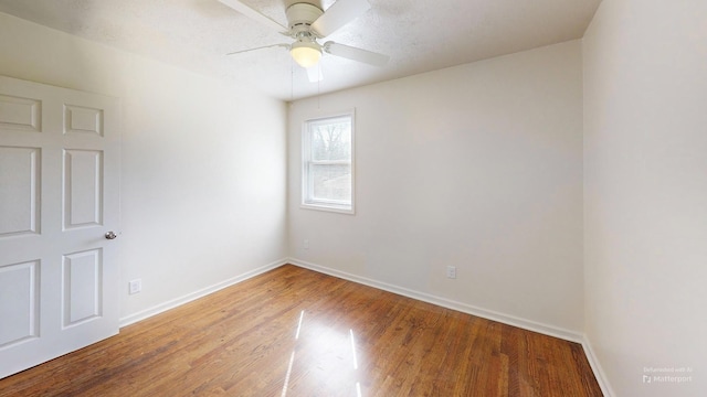 empty room featuring a ceiling fan, baseboards, and wood finished floors