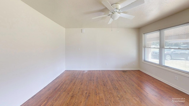 unfurnished room with a textured ceiling, wood finished floors, a ceiling fan, and baseboards