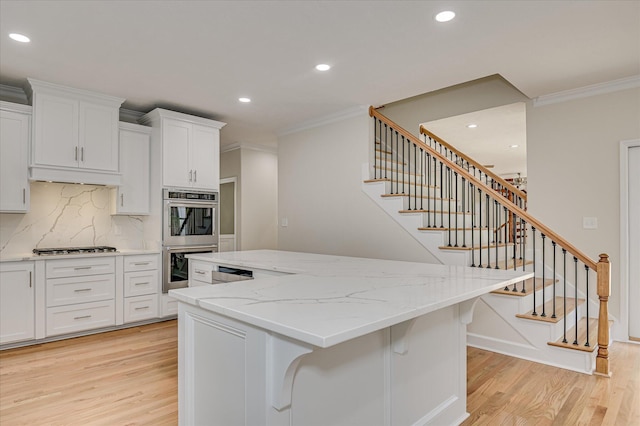 1 Bohler Ave, Evans, GA 30809 - kitchen with appliances with stainless steel finishes, light wood finished floors, a center island, crown molding, and under cabinet range hood