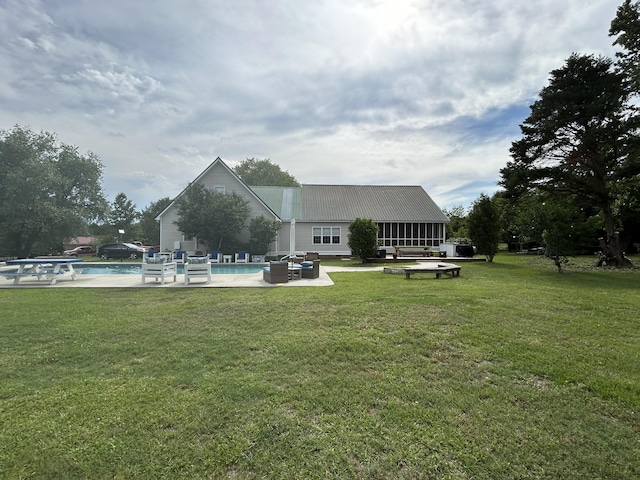 back of property featuring a yard, a patio, an outdoor pool, and metal roof