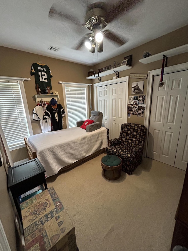 carpeted bedroom with multiple closets and ceiling fan