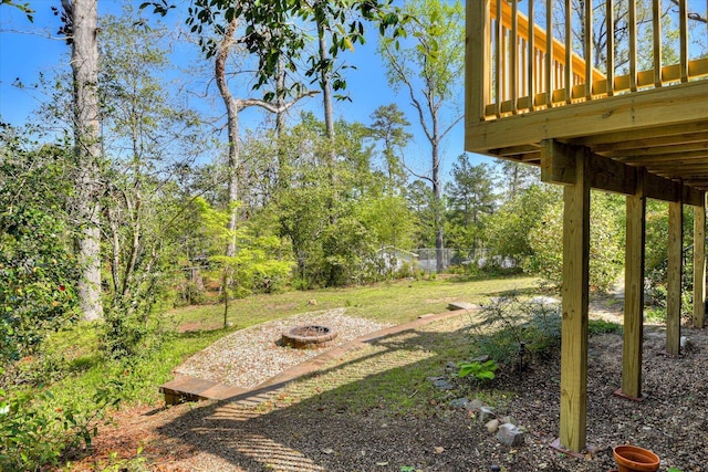 view of yard featuring fence, a wooden deck, and a fire pit