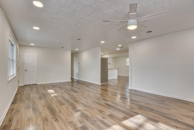 empty room with ceiling fan, light hardwood / wood-style flooring, and a textured ceiling