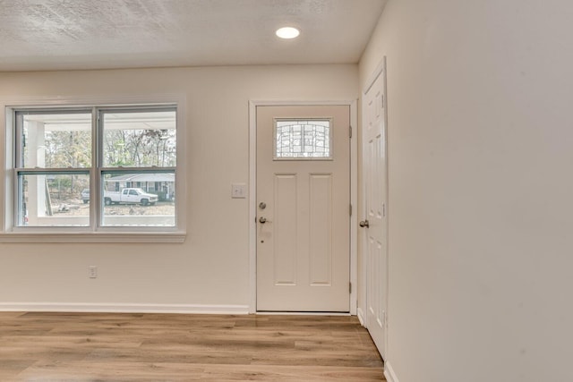 entryway with a textured ceiling and light hardwood / wood-style flooring