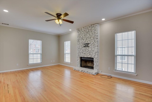 unfurnished living room featuring visible vents, ornamental molding, a stone fireplace, wood finished floors, and baseboards