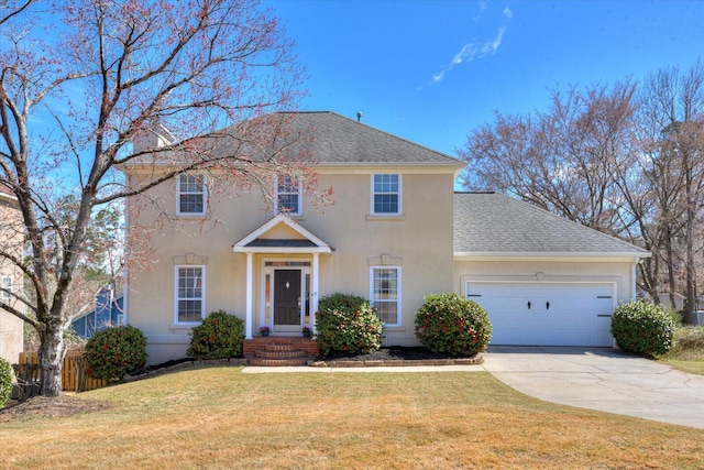 colonial house with concrete driveway, roof with shingles, an attached garage, a front yard, and stucco siding