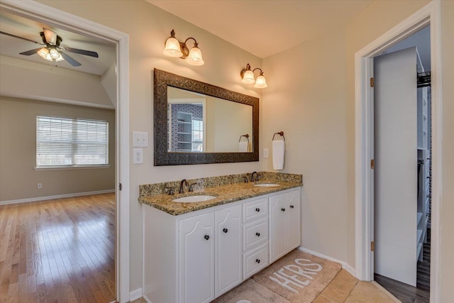 full bath with double vanity, a ceiling fan, baseboards, and a sink