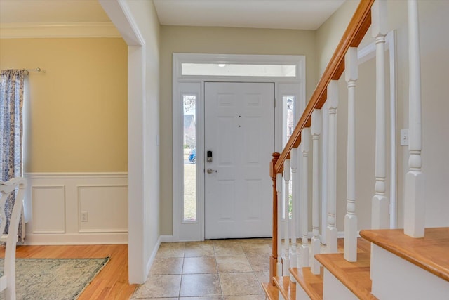 entryway with a wainscoted wall, light wood-style flooring, stairway, and a decorative wall