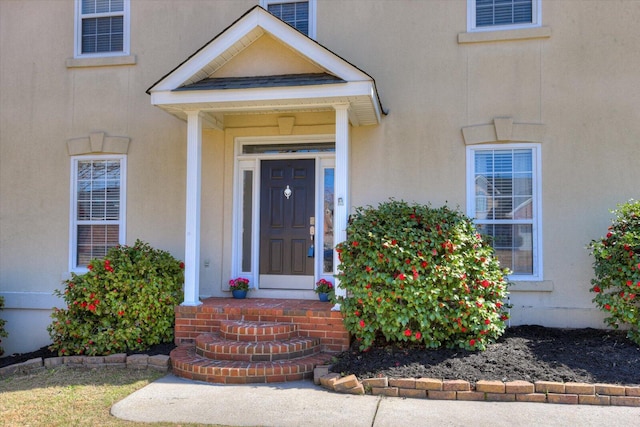 entrance to property with visible vents and stucco siding