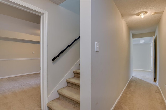 stairway with carpet, a textured ceiling, and baseboards