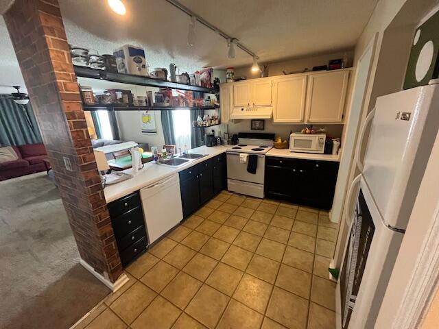 kitchen with white appliances, ornate columns, light tile patterned flooring, light countertops, and under cabinet range hood