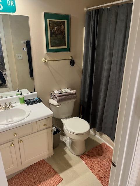 full bathroom featuring a shower with shower curtain, toilet, and vanity