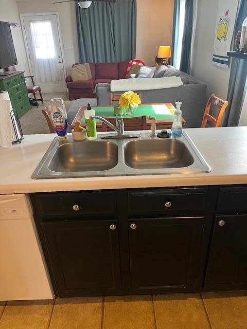 kitchen with a sink, dishwasher, light tile patterned floors, and light countertops