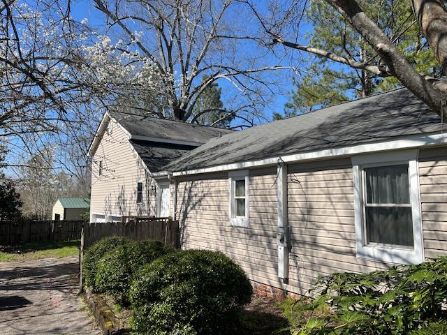 view of home's exterior with fence and a shingled roof