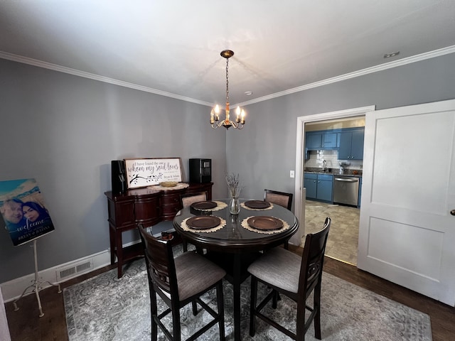 dining space with ornamental molding, wood finished floors, and a chandelier