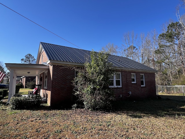 view of property exterior with brick siding, metal roof, and fence