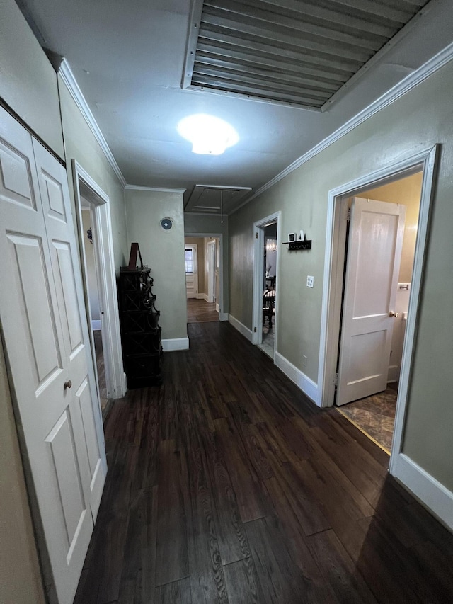 hall featuring attic access, wood finished floors, baseboards, and ornamental molding