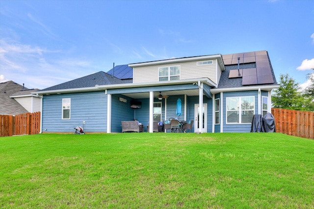 back of house with solar panels, ceiling fan, and a lawn