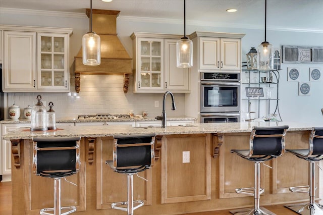 kitchen with a kitchen breakfast bar, backsplash, light stone counters, and an island with sink