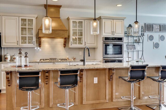 kitchen with a kitchen breakfast bar, backsplash, light stone counters, and an island with sink