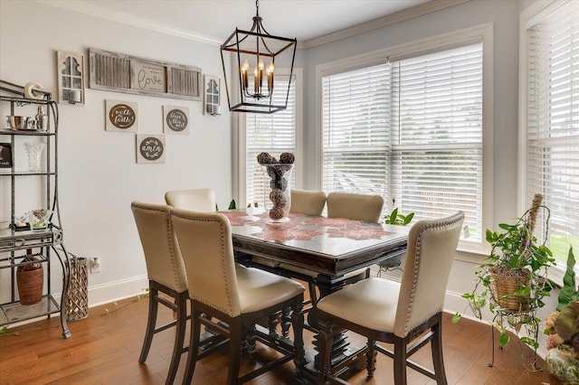 dining area with hardwood / wood-style floors, ornamental molding, and a notable chandelier