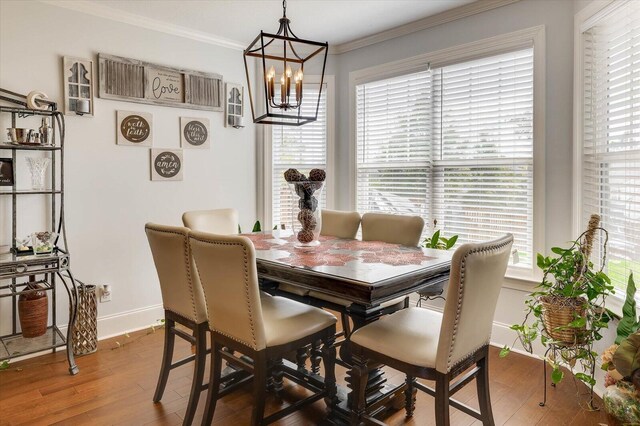 dining area with hardwood / wood-style floors, ornamental molding, and a notable chandelier