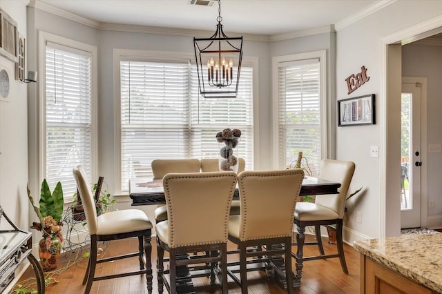 dining area with a notable chandelier, dark hardwood / wood-style flooring, and crown molding