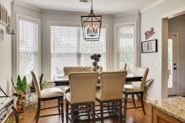 dining area with a notable chandelier, dark hardwood / wood-style flooring, and crown molding