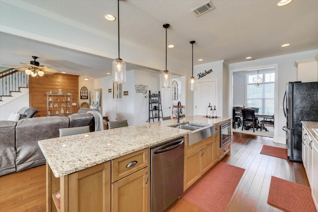 kitchen with stainless steel appliances, ceiling fan, sink, hanging light fixtures, and an island with sink