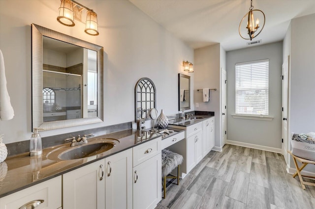 bathroom with wood-type flooring, vanity, an enclosed shower, and a notable chandelier