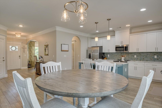 dining room featuring a notable chandelier, light wood-type flooring, and ornamental molding